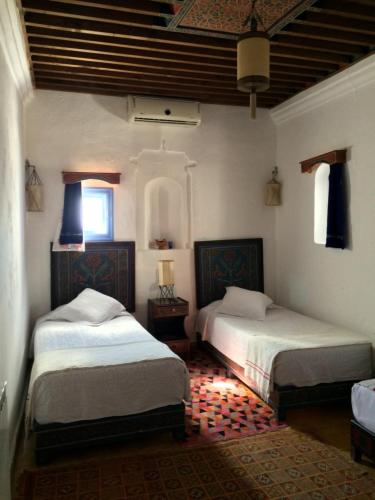 a bedroom with two beds and a room with two windows at Casa Perleta in Chefchaouene