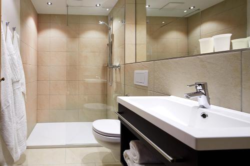 a bathroom with a sink and a toilet and a shower at Hotel Wieser in Mittersill