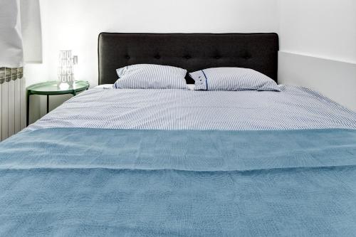 a bed with a blue comforter and two pillows at Apartments Viola in Zagreb