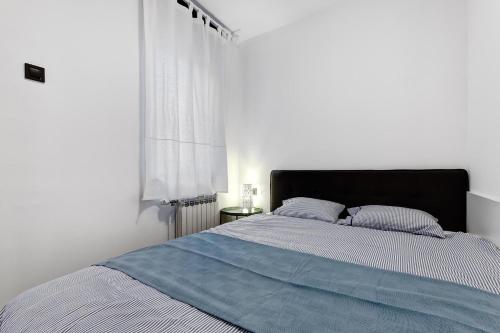 a white bedroom with a large bed with blue sheets at Apartments Viola in Zagreb
