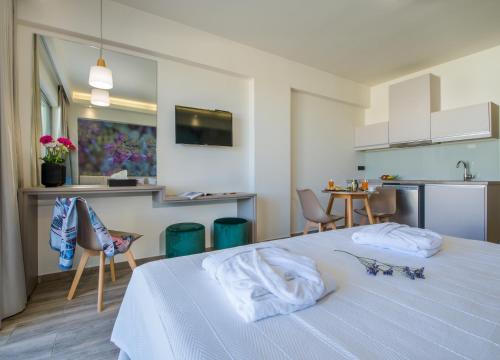 a bedroom with a white bed and a kitchen at Incognito Creta Luxury Suites and More in Kolymvari