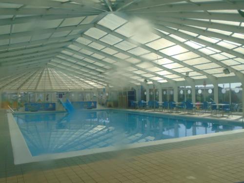 a large swimming pool with blue tables and chairs at Lyntons 3 bedroom caravan pets stay free in Heacham