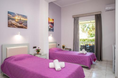two beds in a room with purple sheets and a window at Tom & John Center in Tsilivi