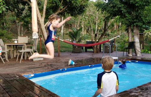 uma rapariga a saltar para uma piscina com um rapaz em Maya Hill Lodge em Black Man Eddy