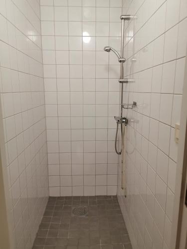 La salle de bains est pourvue d'une douche et de murs en carrelage blanc. dans l'établissement IzKaMaGe Hotel 2, à Västerås