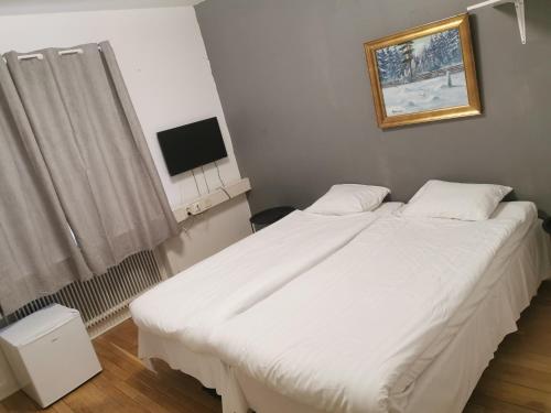 een groot wit bed in een kamer met een televisie bij IzKaMaGe Hotel 2 in Västerås