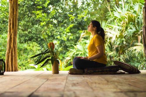 a woman sitting on a wooden floor in meditation at Cotococha Amazon River Lodge in Tena