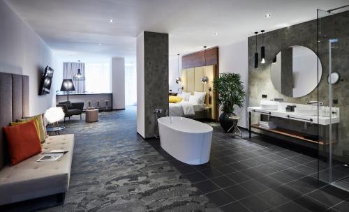a large bathroom with a tub and a bedroom at Hotel Neuer Fritz in Berlin