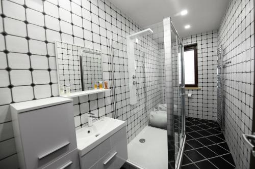 a white tiled bathroom with a sink and a shower at Atrium-Accomm in Řitka