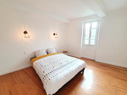 a white bedroom with a bed and a window at Appartement de charme climatisé in Graulhet