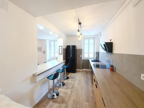 eine Küche mit einer Theke und Hockern in einem Zimmer in der Unterkunft Appartement de charme climatisé in Graulhet