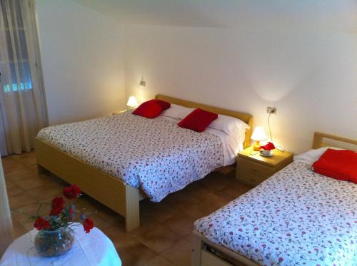 a bedroom with two beds with red pillows on them at Residence Geranio in Domaso