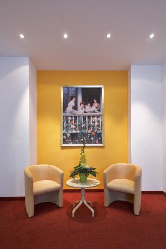 a room with two chairs and a table and a painting at Hotel ADRIA München in Munich