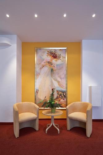two chairs and a table in a room with a painting at Hotel ADRIA München in Munich