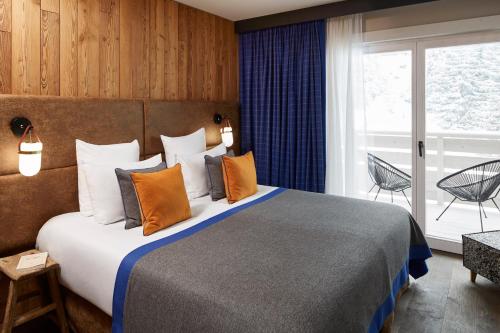 a hotel room with a large bed and a balcony at Ecrin Blanc Resort Courchevel - Aquapark in Courchevel