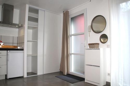 a kitchen with white cabinets and a mirror and a window at Rez de Jardin Terrasse Literie Haut de gamme Proche Gare et Hyper Centre in Quimper