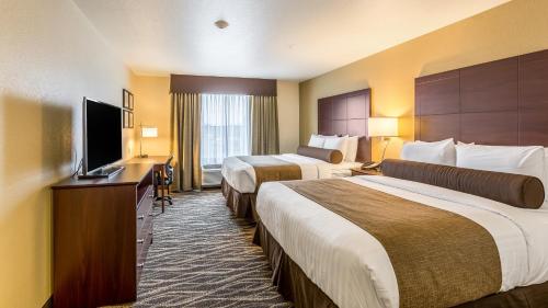 a hotel room with two beds and a flat screen tv at Cobblestone Hotel & Suites - Chippewa Falls in Chippewa Falls