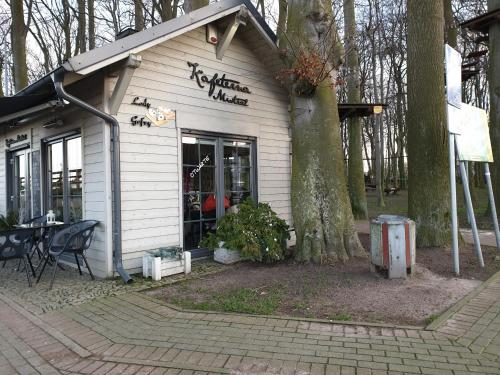 a small building with a table and a tree at Apartament "Złoty relaks" tuż przy plaży z balkonem z widokiem na Hel i hamakami in Puck