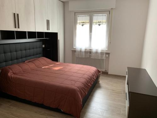 a bedroom with a red bed and a window at Casa Chiara Andalo Centro in Andalo