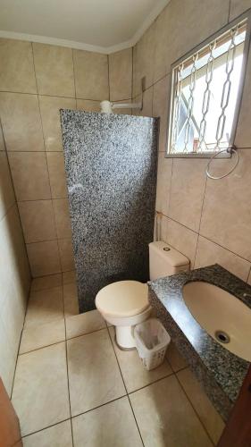 a bathroom with a toilet and a sink and a window at Delta Hotel in Andradina
