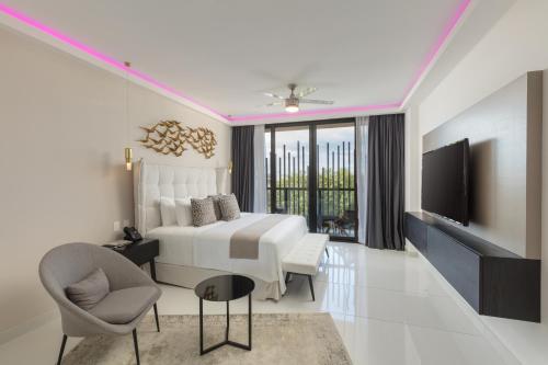 a bedroom with a bed and a tv and a chair at Serenity Hotel Boutique By Alsol in Playa del Carmen