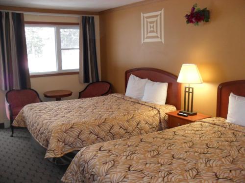 a hotel room with two beds and a window at Forest Plaza Motel in Mount Forest