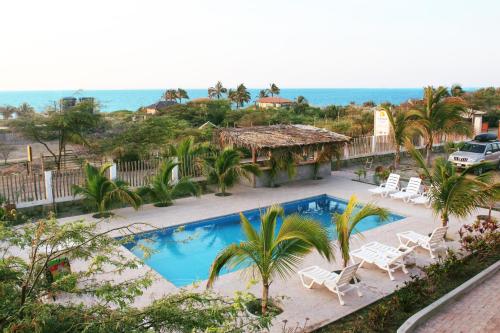 a resort with a swimming pool and chairs and the ocean at Hotel Casa Vichayo in Vichayito