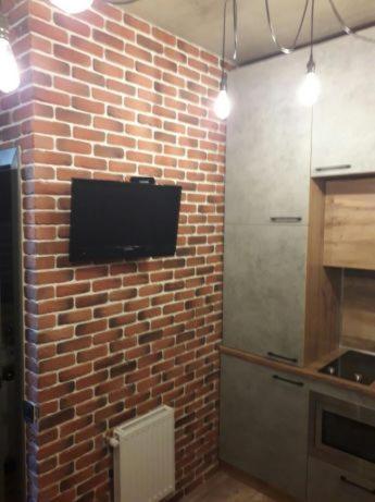 een keuken met een bakstenen muur en een televisie bij ОДНОКОМНАТНЫЙ ЛОФТ НА 26 ЭТАЖЕ in Odessa