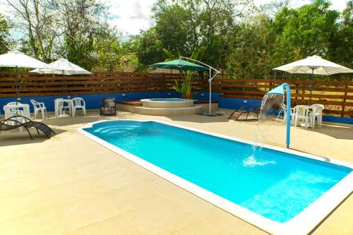 a swimming pool with a fountain and chairs and umbrellas at João e Maria Restaurante e Chalés in Tiradentes