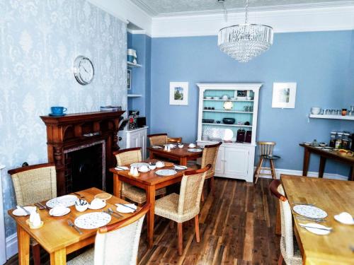a dining room with blue walls and wooden tables at Treventon Guest House in Penzance
