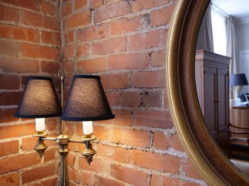 two lamps against a brick wall with a mirror at Hotel Bonaparte in Montréal
