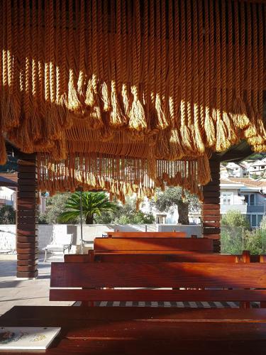 a group of benches sitting under a wooden roof at Sun Village Aparthotel in Herceg-Novi