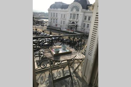 - une table sur un balcon avec vue sur un bâtiment dans l'établissement Le studio de la mer, à Trouville-sur-Mer