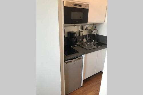 une cuisine avec un évier et un micro-ondes dans l'établissement Le studio de la mer, à Trouville-sur-Mer