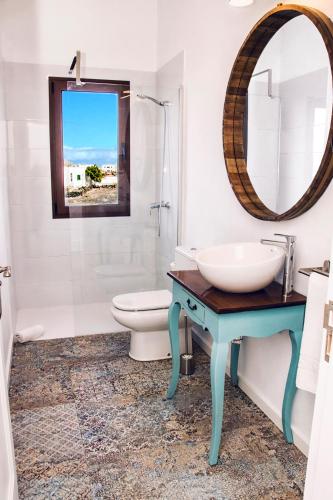 a bathroom with a sink and a toilet and a mirror at Casa De La Nobleza in Tinajo