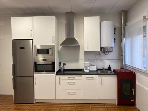 eine Küche mit weißen Schränken und einem Kühlschrank aus Edelstahl in der Unterkunft Apartamentos el Balcon del Cañon Valdemaluque in Valdemaluque