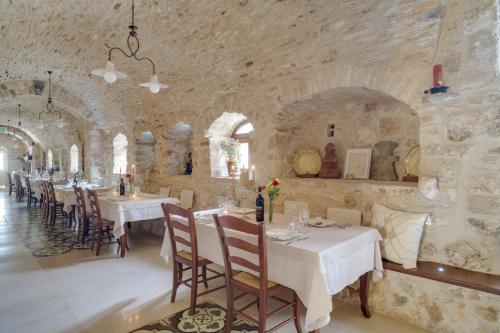 a dining room with tables and chairs in a stone wall at Masseria Storica Pilapalucci in Toritto
