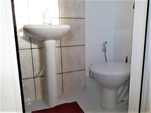 um banheiro com uma pia branca e um vaso sanitário em Aconchego - Família Mangas Monteiro em Macapá