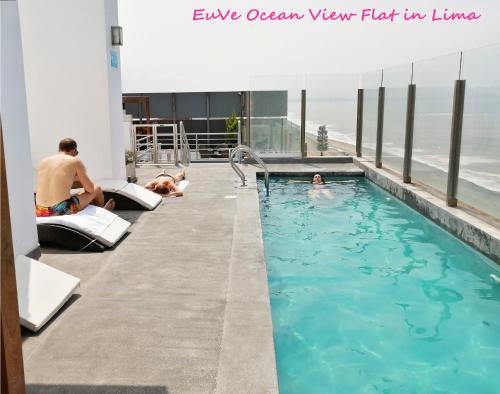 利马EuVe Ocean View Flat in Lima的一座建筑物屋顶上的游泳池,里面的人