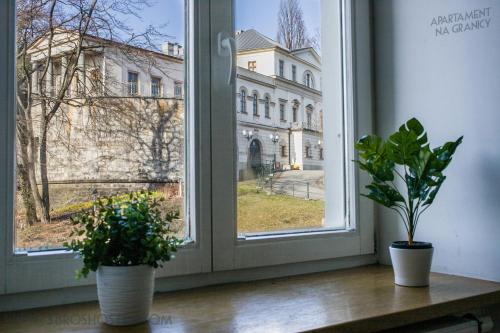 two plants sitting on a window sill looking out at a building at Apartament na Granicy / Apartment on the border in Cieszyn