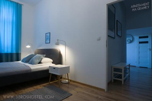 a bedroom with a bed with a nightstand and a table at Apartament na Granicy / Apartment on the border in Cieszyn