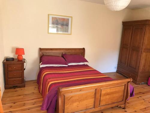 ein Schlafzimmer mit einem Bett mit lila Kissen und einer Kommode in der Unterkunft Le Milieu Chai, Chateau de Charras in Charras