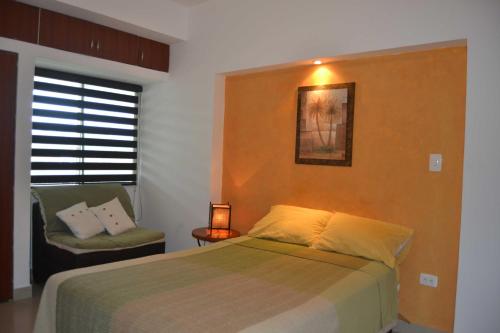 a bedroom with a bed and a chair and a window at Suite frente al mar Playa Azul in Tonsupa