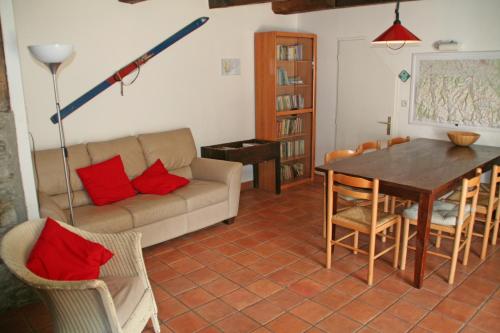 een woonkamer met een bank en een tafel met rode kussens bij Comfortable farm house Petit Barzun, in the Parc National Pyrenees in Barèges