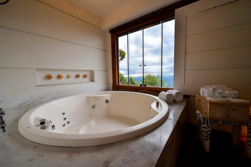 a large bath tub in a bathroom with a window at Pousada Estalagem do Mirante in Brumadinho
