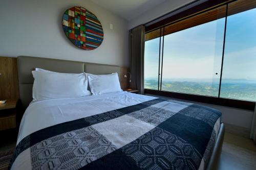 a bedroom with a bed and a large window at Pousada Estalagem do Mirante in Brumadinho