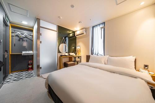 a bedroom with a large white bed and a bathroom at Hotel DDK in Seoul
