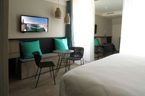 マルセイユにあるBest Western Plus Hôtel La Jolietteのベッド、テーブル、椅子が備わるホテルルームです。