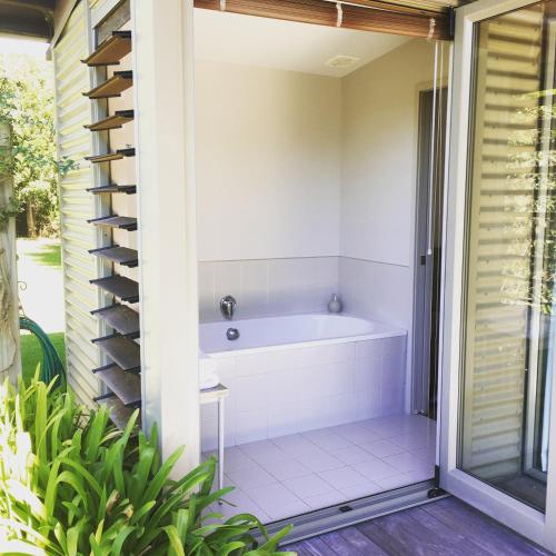 a bath tub in a bathroom with a window at Coastal Cottage Retreat - Te Awanga Cottages in Te Awanga