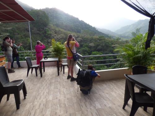 a group of people standing on a balcony looking at the mountains at Hostal Alto de la Montaña in Minca